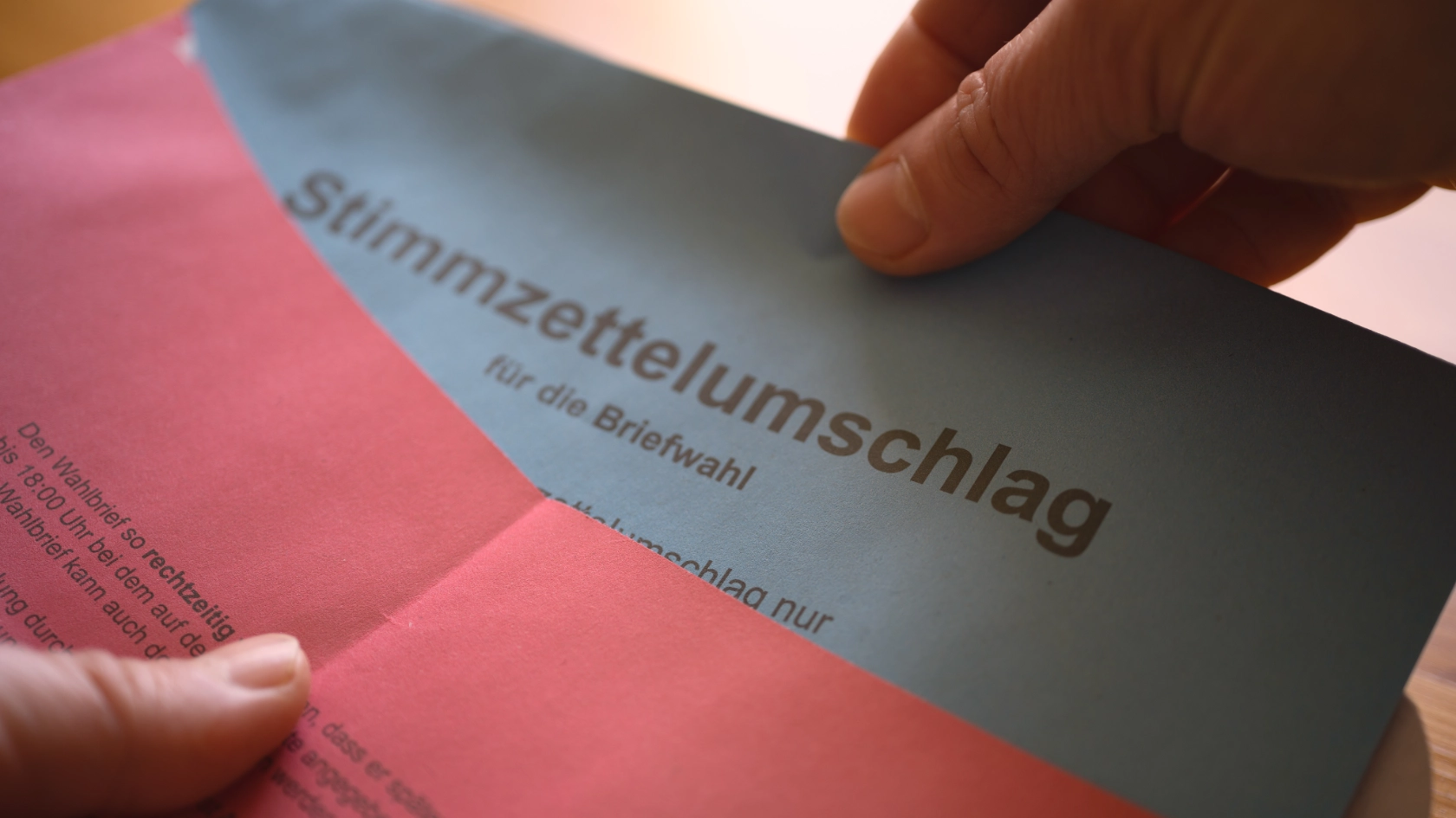 Nahaufnahme der Hände beim Schließen des Briefwahlumschlags
